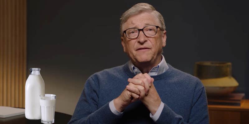 Bill Gates sitting next to a table with a glass of milk on it