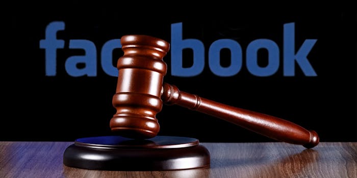 Wooden gavel focused in foreground on wooden table, facebook logo blurred behind on black background