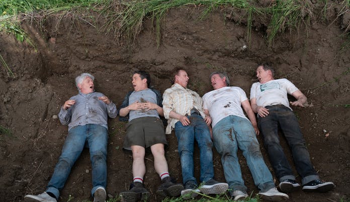 five men laying in dirt