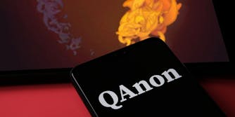 QAnon word logo on black phone with ipad behind website logo QPATRIOT.ORG on red background