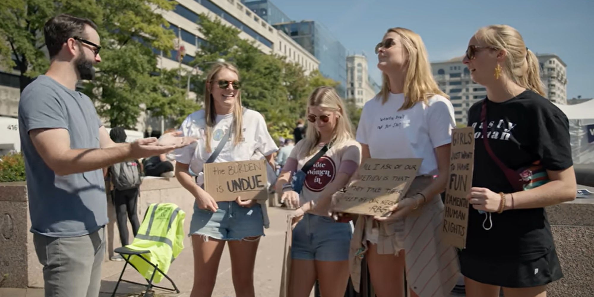 Matt Walsh standing outside talking to protesting women holding signs