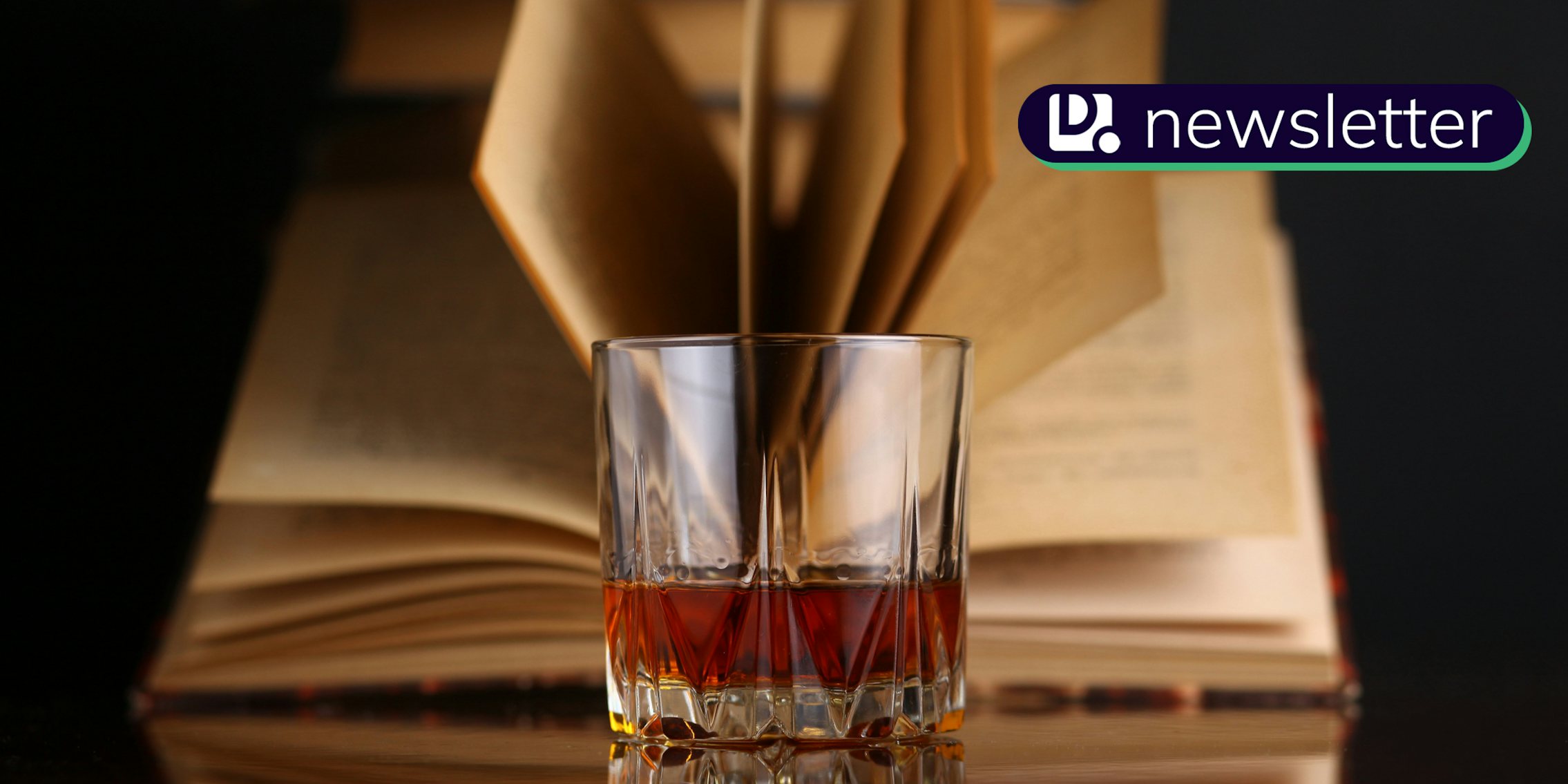 Glass of whiskey on a reflective surface with books. The Daily Dot newsletter logo is in the top right corner.