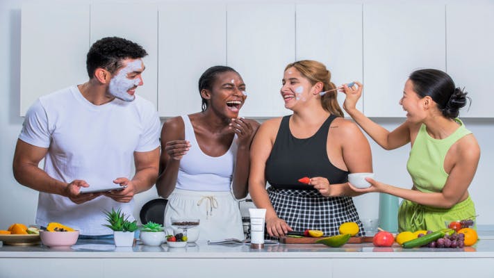 Four friends, a male and three females, laughing together with a diy face mask on their faces
