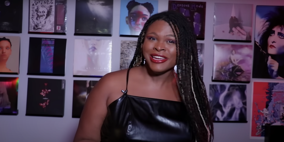 image of youtuber kat blaque in a black tank top standing in a living room.