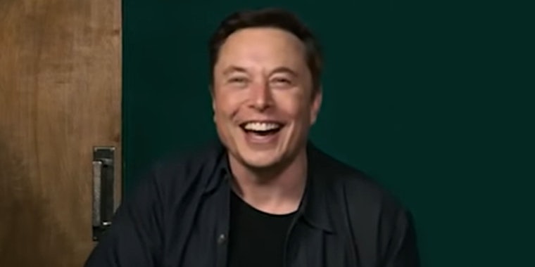Elon Musk laughing dark green wall with door behind