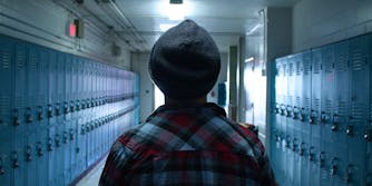 student in beanie and flannel walking down hallway with lockers