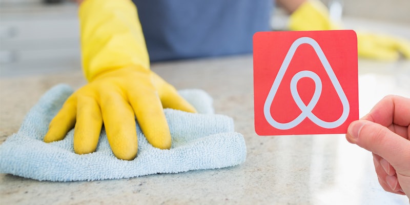 hand with glove wiping counter top with rag hand on right side holding Airbnb logo on square