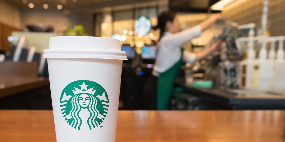 Starbucks coffee cup on counter in front of employee