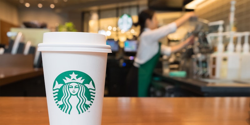 Starbucks coffee cup on counter in front of employee