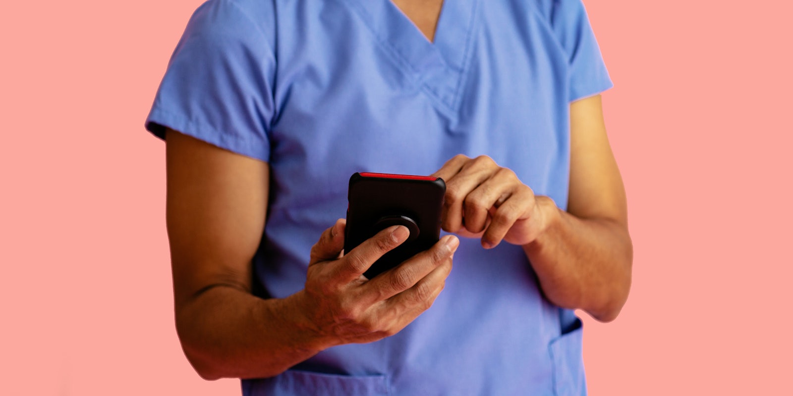 nurse holding cell phone on light pink background