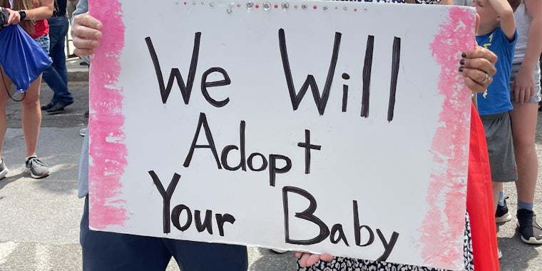 sign that reads 'we will adopt your baby'