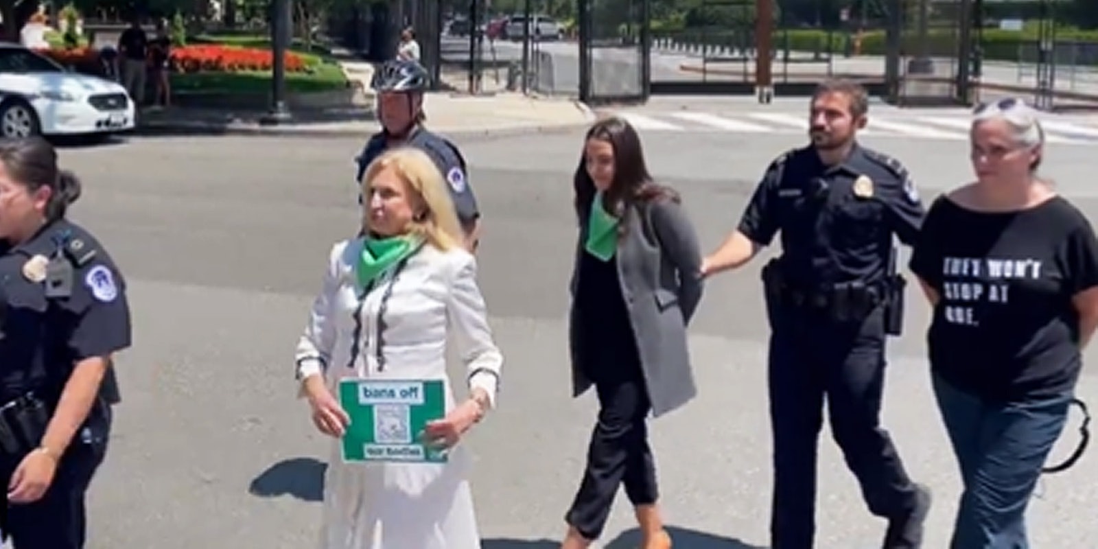 AOC and another woman arrested police walking holding arms of both women