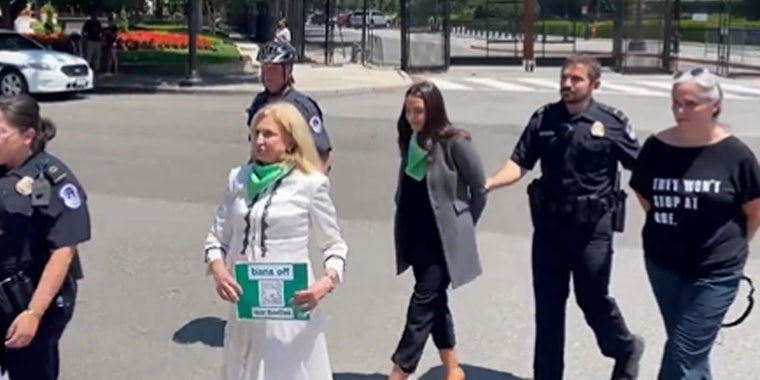 AOC and another woman arrested police walking holding arms of both women