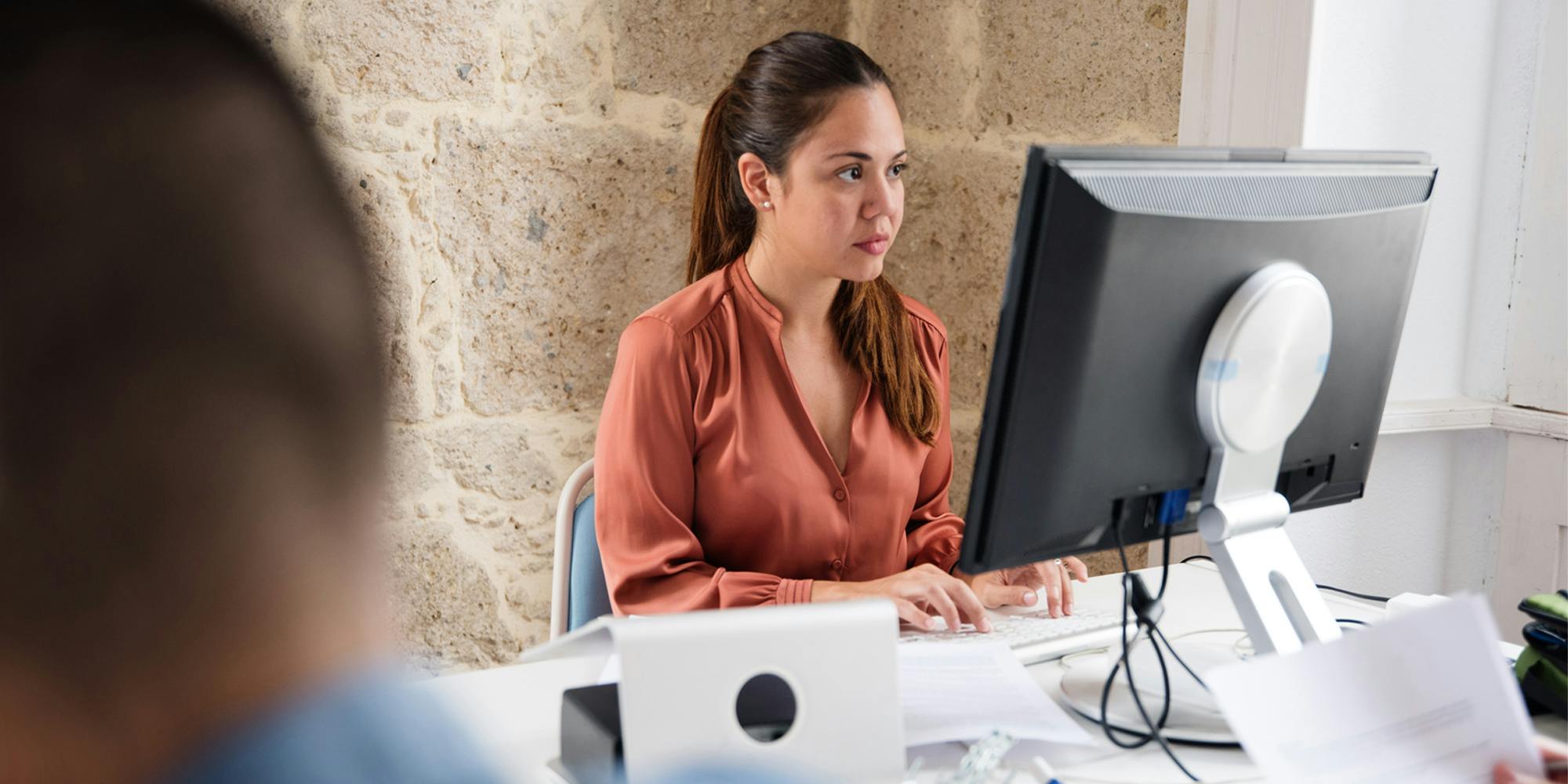 woman with long hair at office job man blurred in foreground