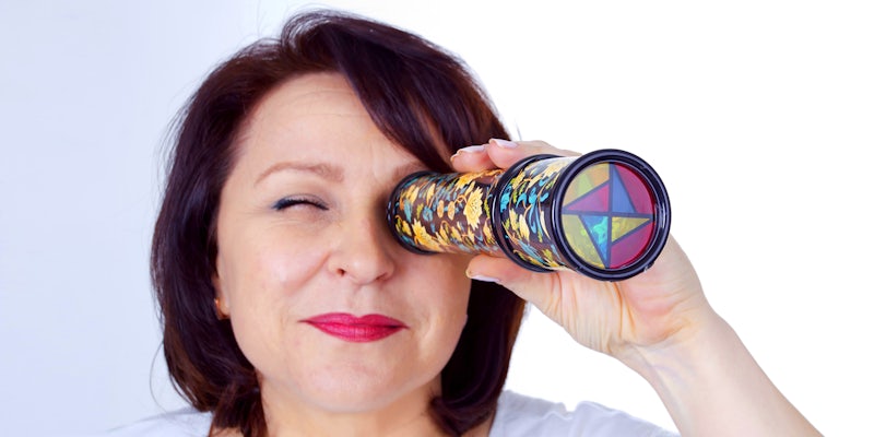 Adult woman looking into a kaleidoscope on a white background
