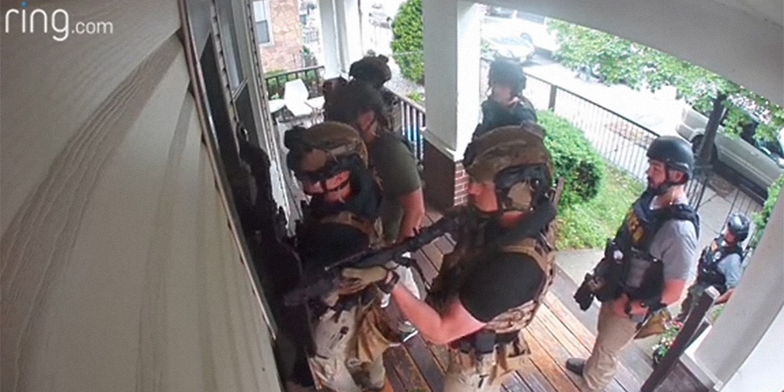 police in riot gear pointing shotguns through porch windows
