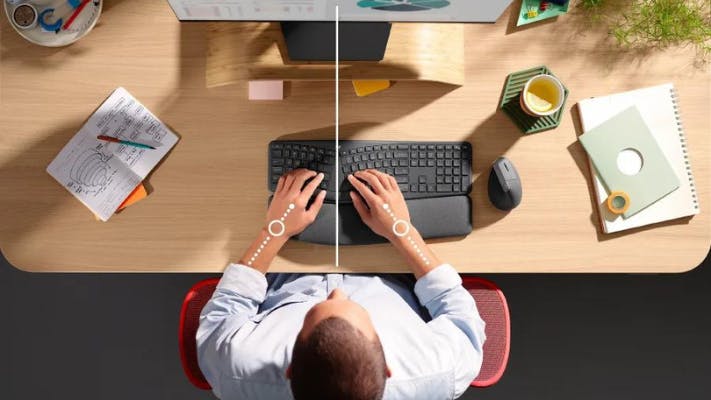 Man sitting at desk using ergonomic keyboard and mouse from Logitech Ergo Series