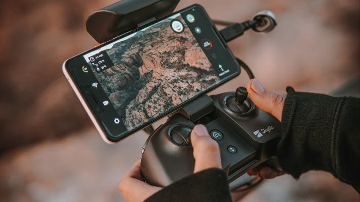 Hands holding controller for a Skydio drone attached to a smartphone