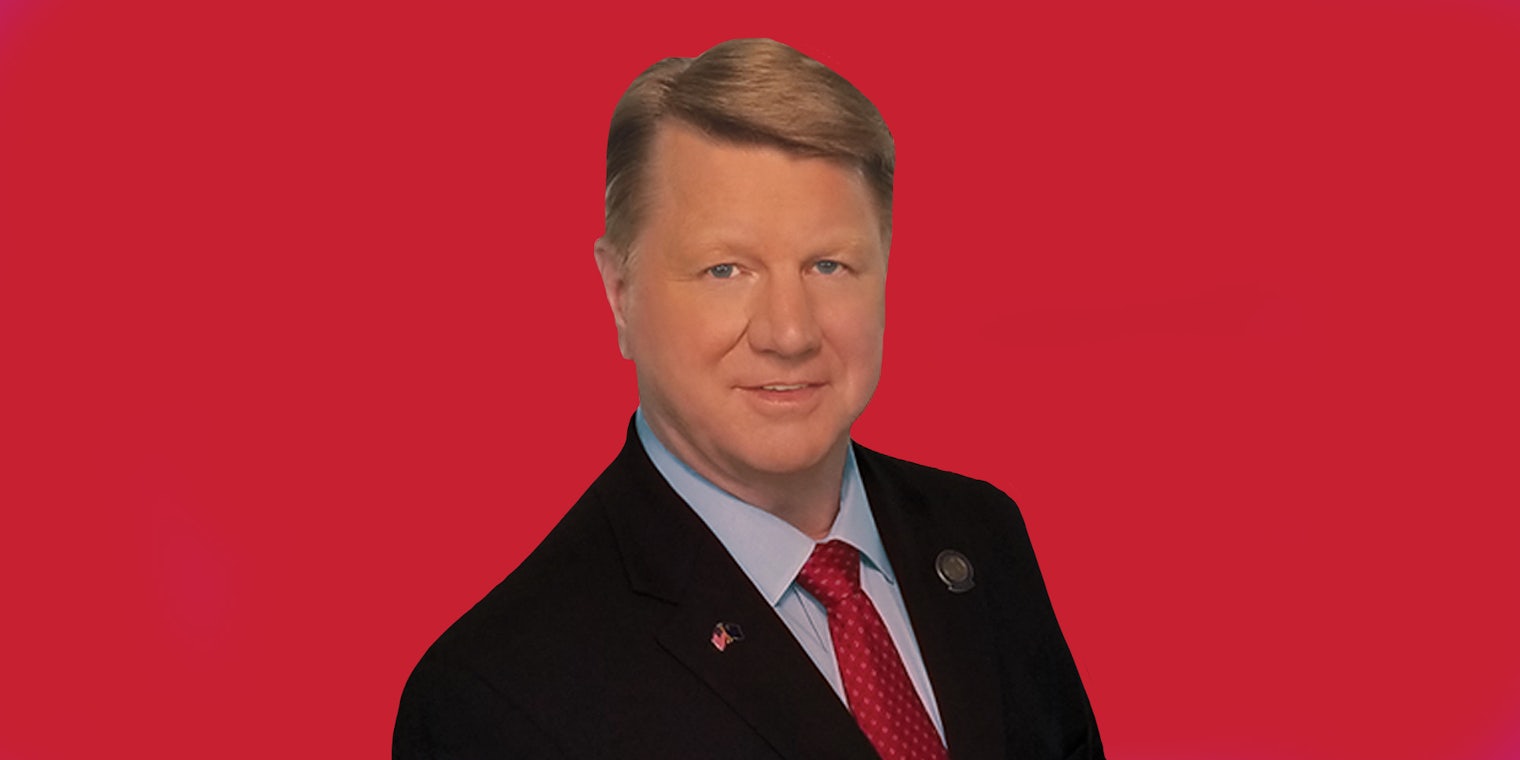 Jim Marchant in suit on red background