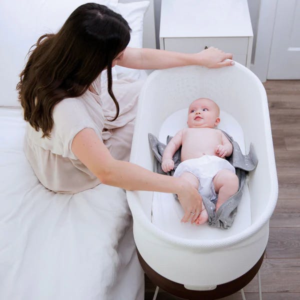 Mother looking at her baby sleeping in SNOO Baby Bassinet and Sleeper.