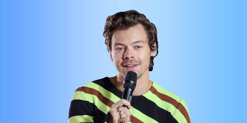 Harry Styles holding microphone singing on light blue gradient background