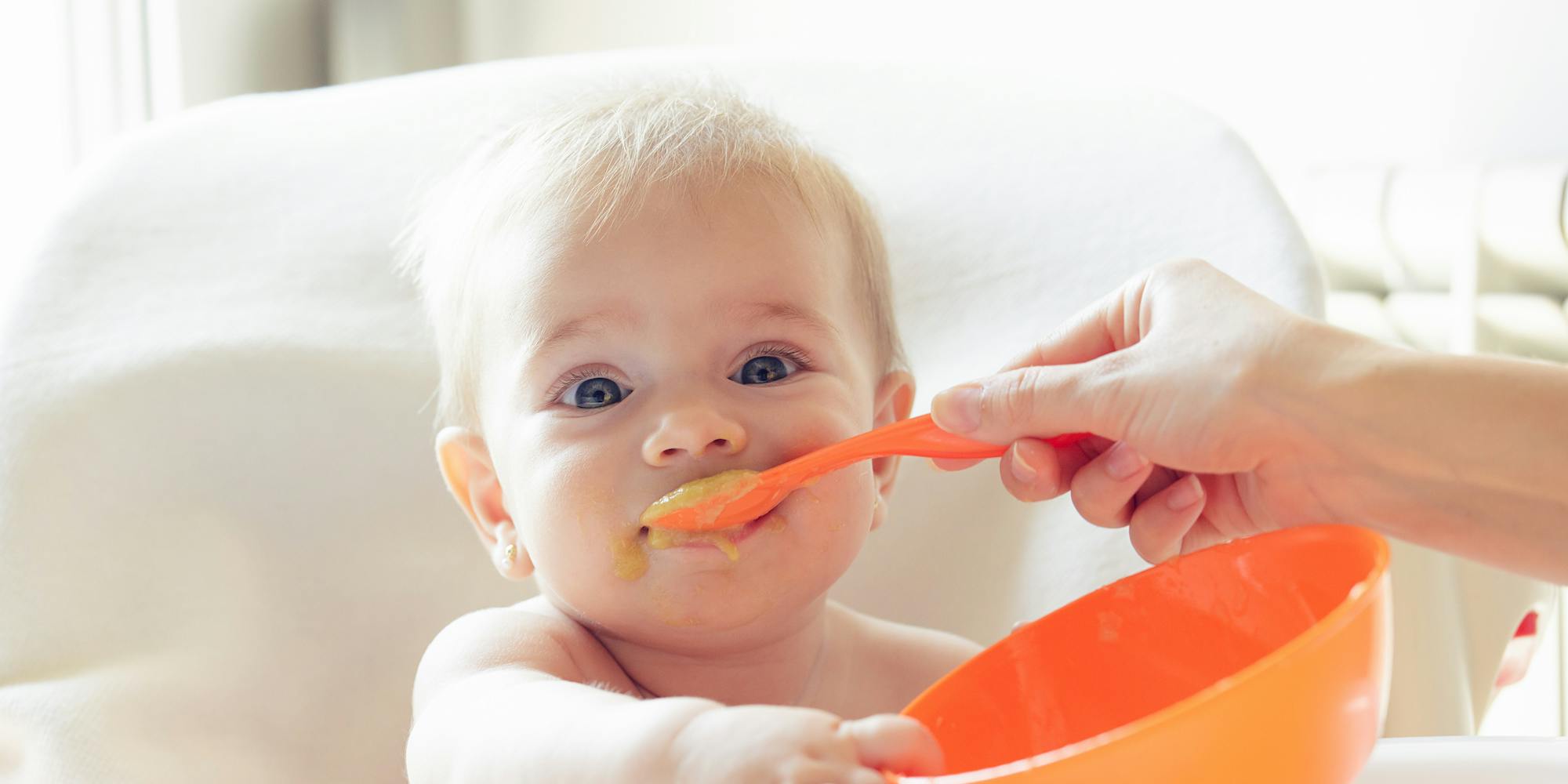 baby eating mush out of bowl