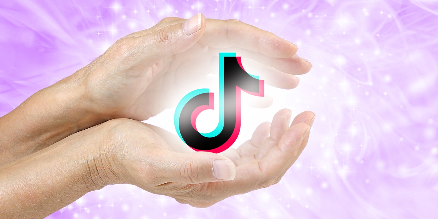hands holding a glowing TikTok logo over a cosmic background