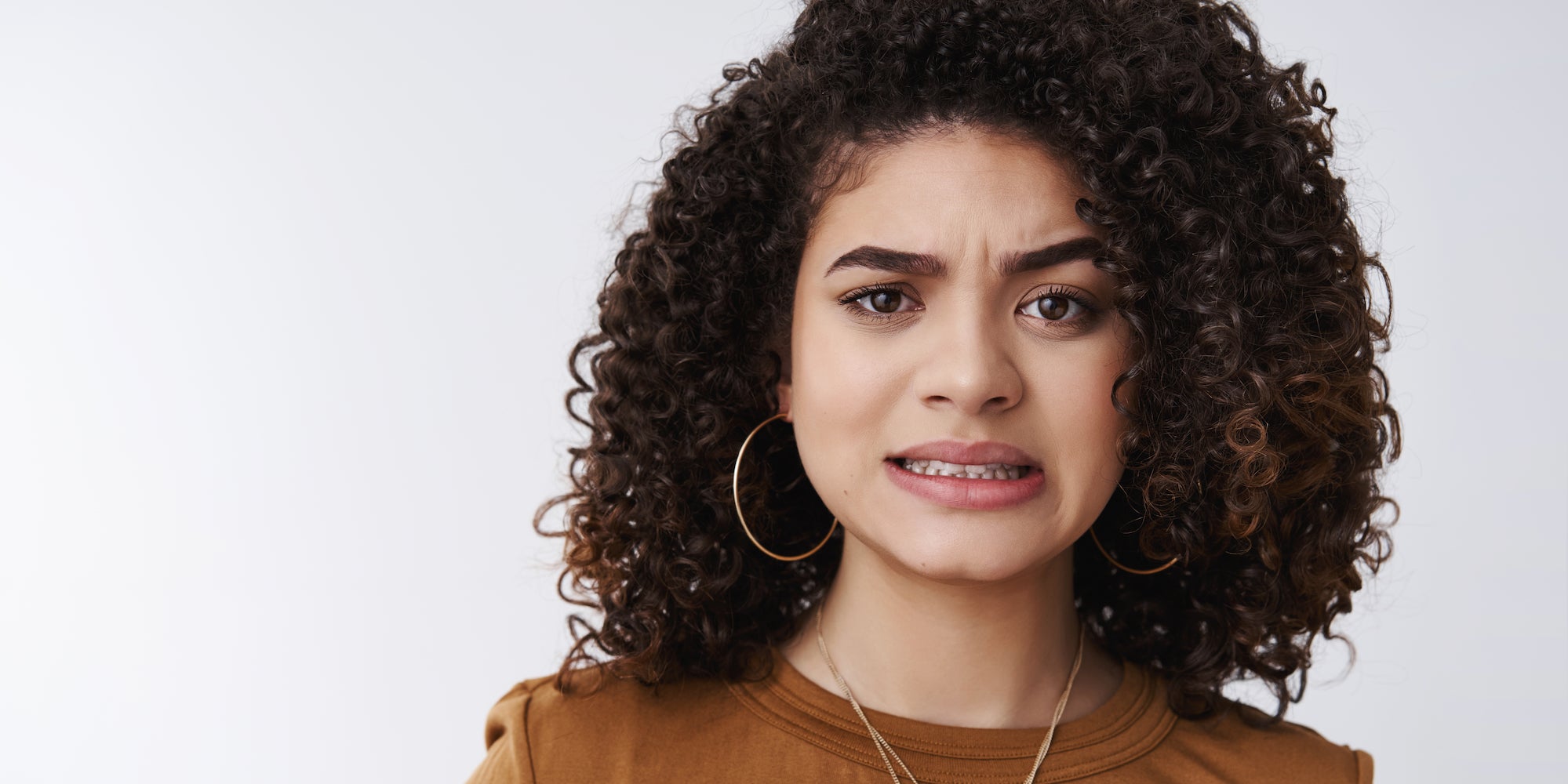 Woman clenching teeth with an eyebrow raised.