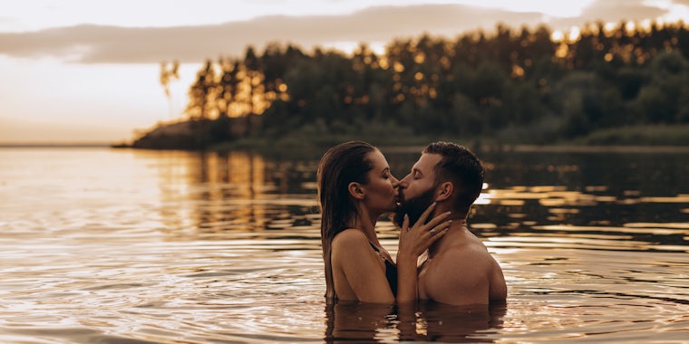 Romantic photo session in the water. A guy and a girl swim in the lake in the evening. Beautiful sunset.