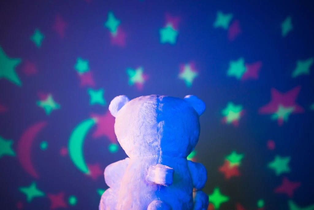 Sound Soother Bear Night Light and Star Projector displaying stars on a dark wall.
