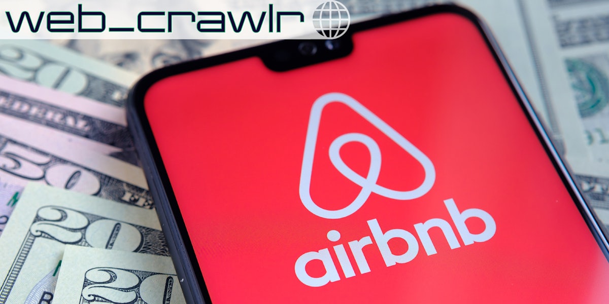 A phone displaying the Airbnb logo on it laying on top of money. The Daily Dot newsletter web_crawlr logo is in the top left corner.