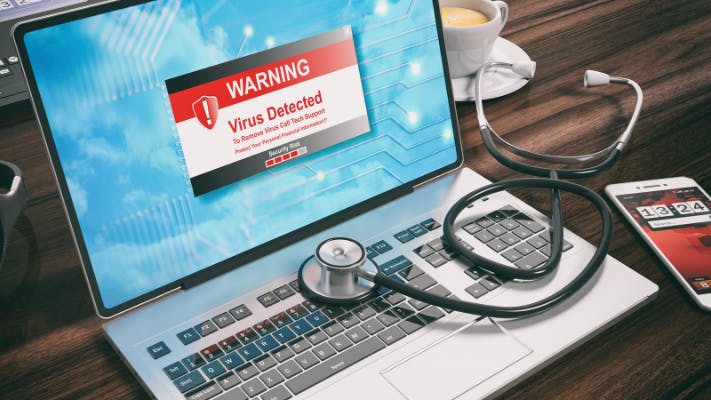 Virus detected text alert on a laptop computer screen and a stethoscope