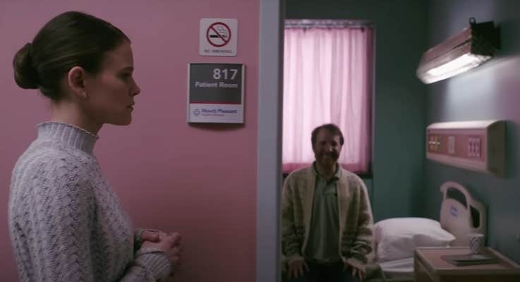 A woman standing outside a hospital room