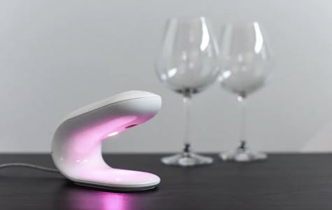 pulse warming system with mood light activated sitting on a table with two wine glasses in the background.
