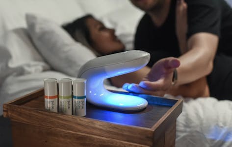 two people in bed, hand reaching under pulse warming system