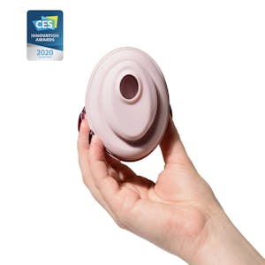 a hand holding the baci clitoral vibrator by lora dicarlo with a stamp from the 2020 consumer electronics show indicating the product won an innovation award