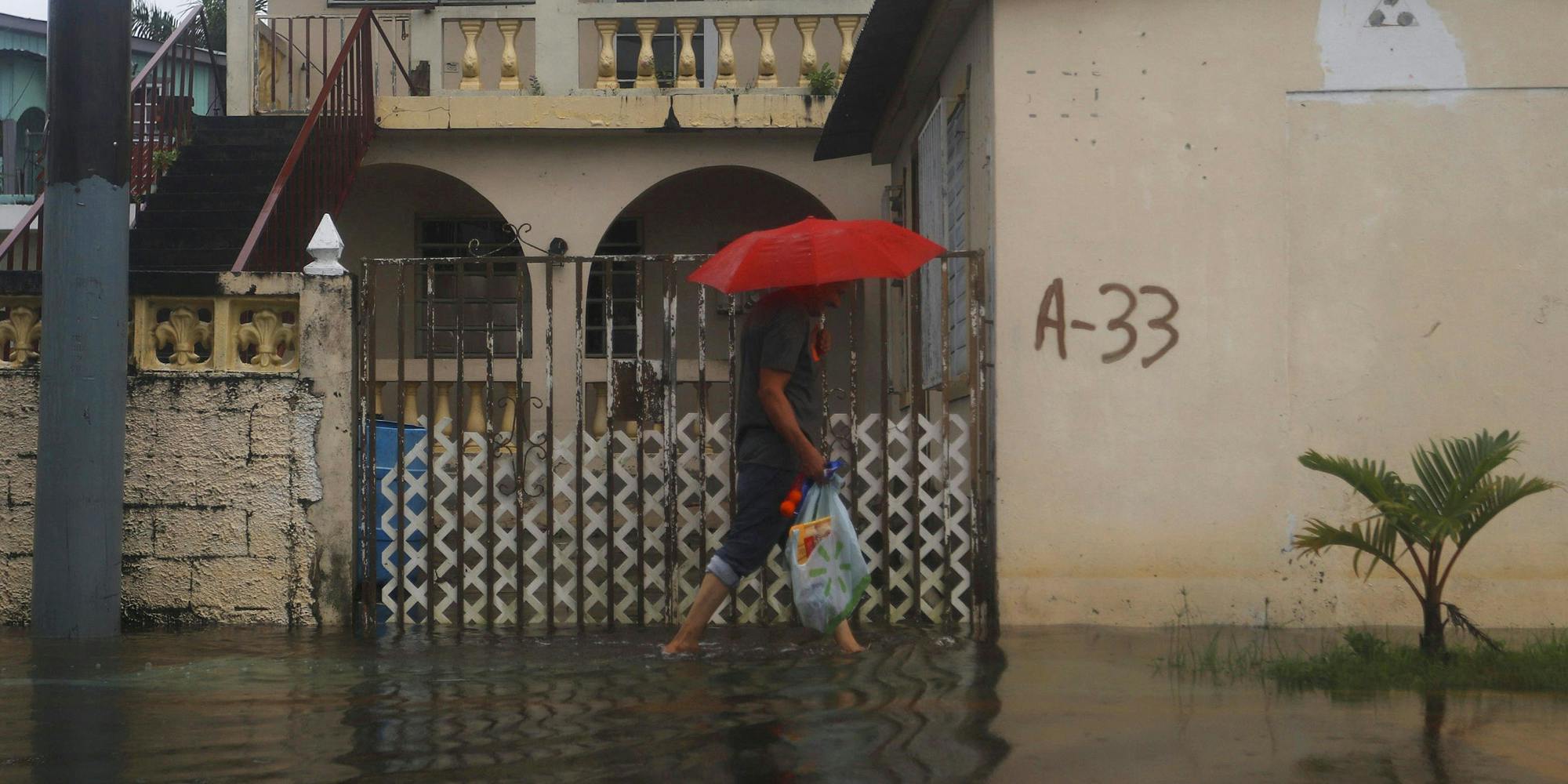 Aftermath of hurricane Fiona in Puerto Rico person walking in flooded street with umbrella