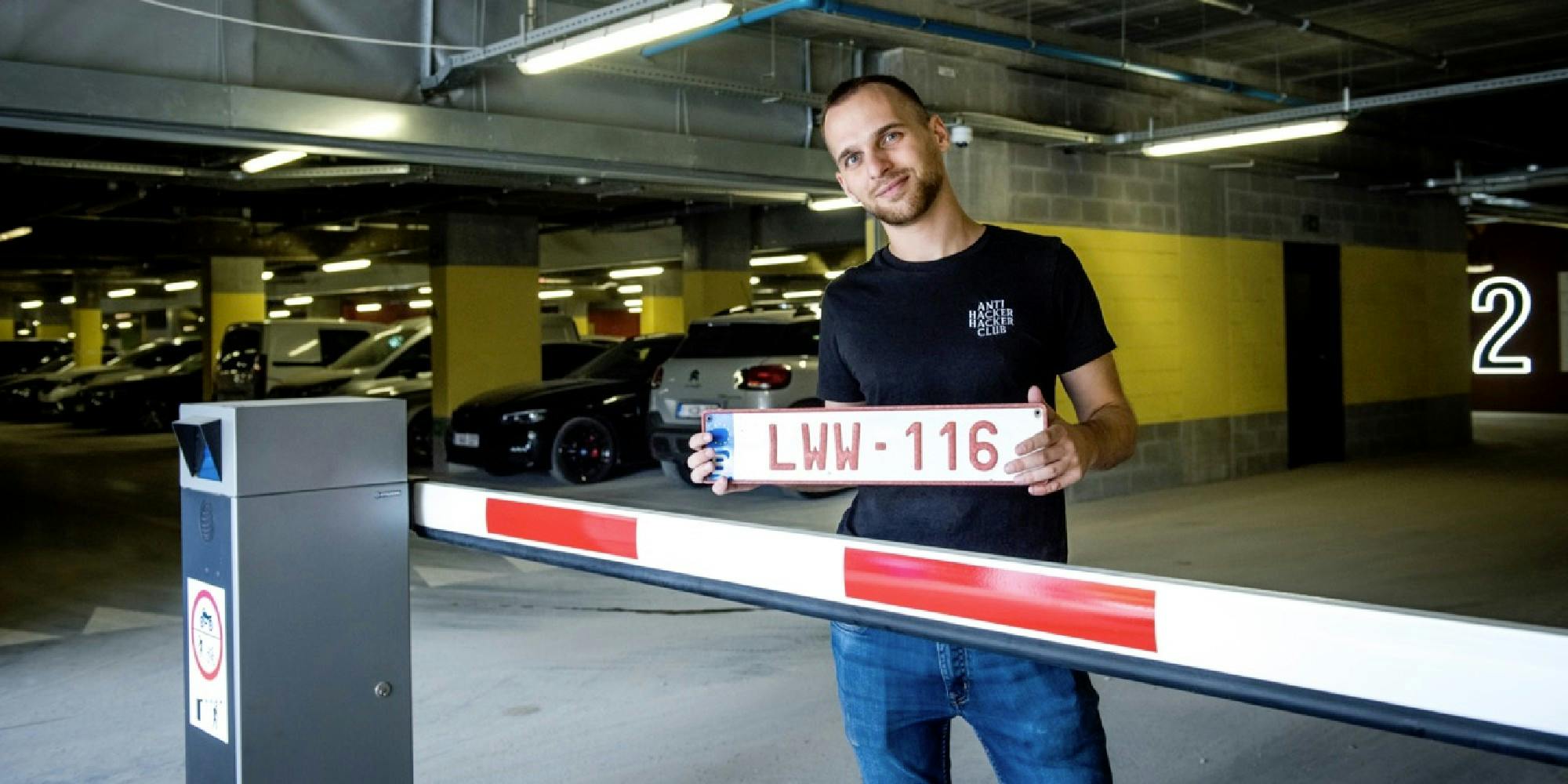 A man holding a license plate in a parking garage