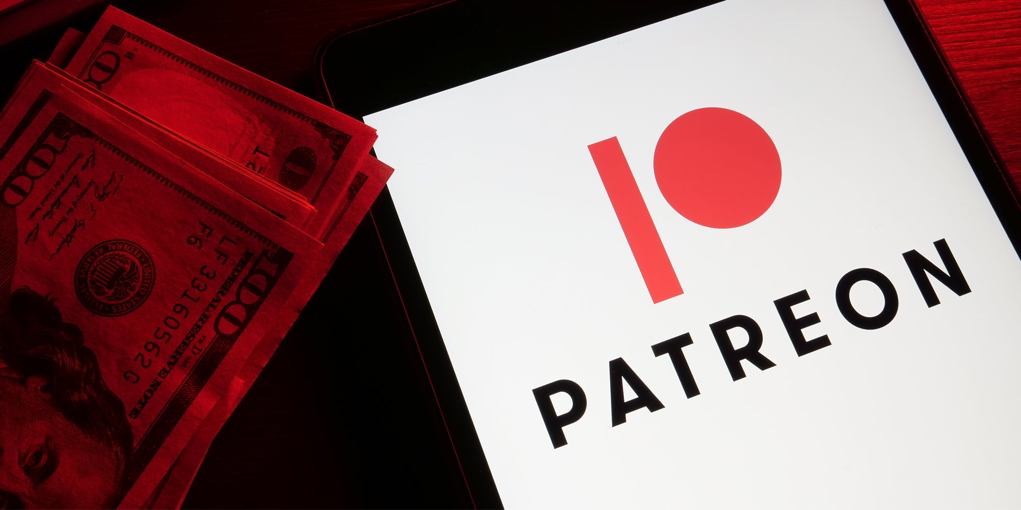 Patreon open on phone with 100 dollar bills to the left with red lit money and background