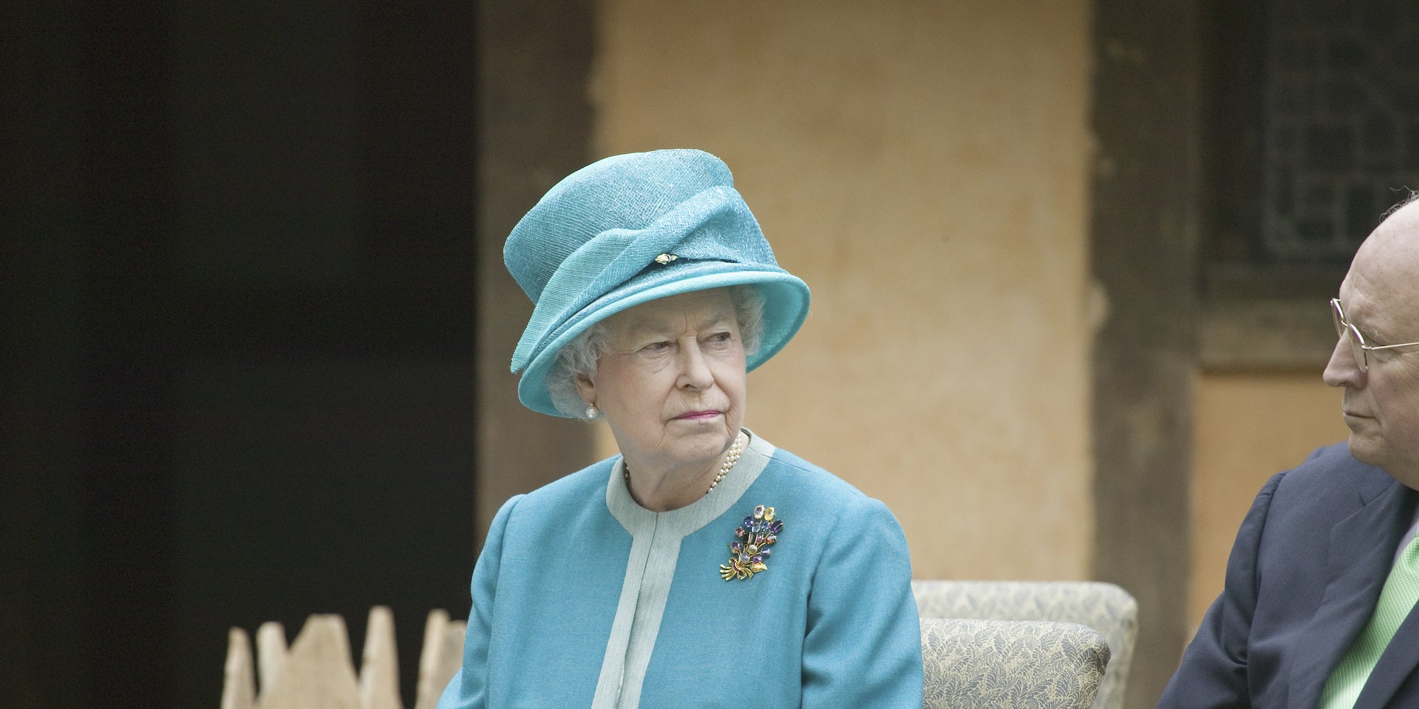 the late queen elizabeth ii riding in a car with a blue suit and hat on