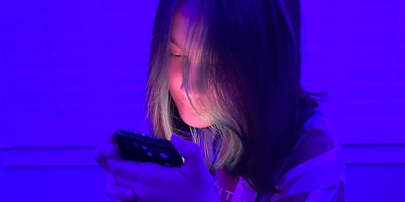 Young girl with her face illuminated by a cell phone light