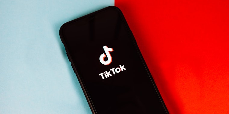 TikTok app opening on phone on half blue half red background