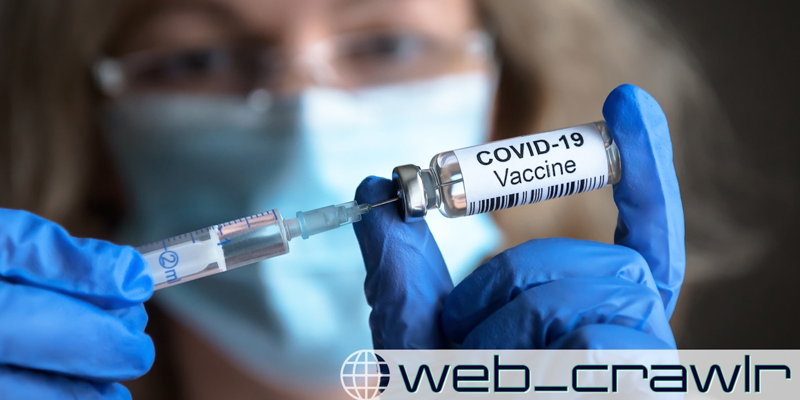 COVID-19 vaccine in researcher hands, female doctor's holds syringe and bottle with vaccine. The Daily Dot newsletter web_crawlr logo is in the bottom right corner.