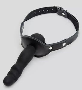 Bondage Boutique gag with a ball on the mouth side and a dildo on the other side against a grey background.