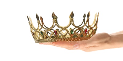 hands holding gold crown on white background