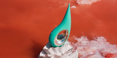an aqua Lelo dot vibrator perched on top of a white seashell
