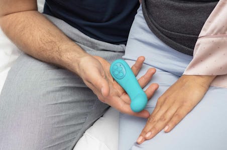 Close up of a man holding a mysteryvibe POCO flexible vibrator sitting beside a woman
