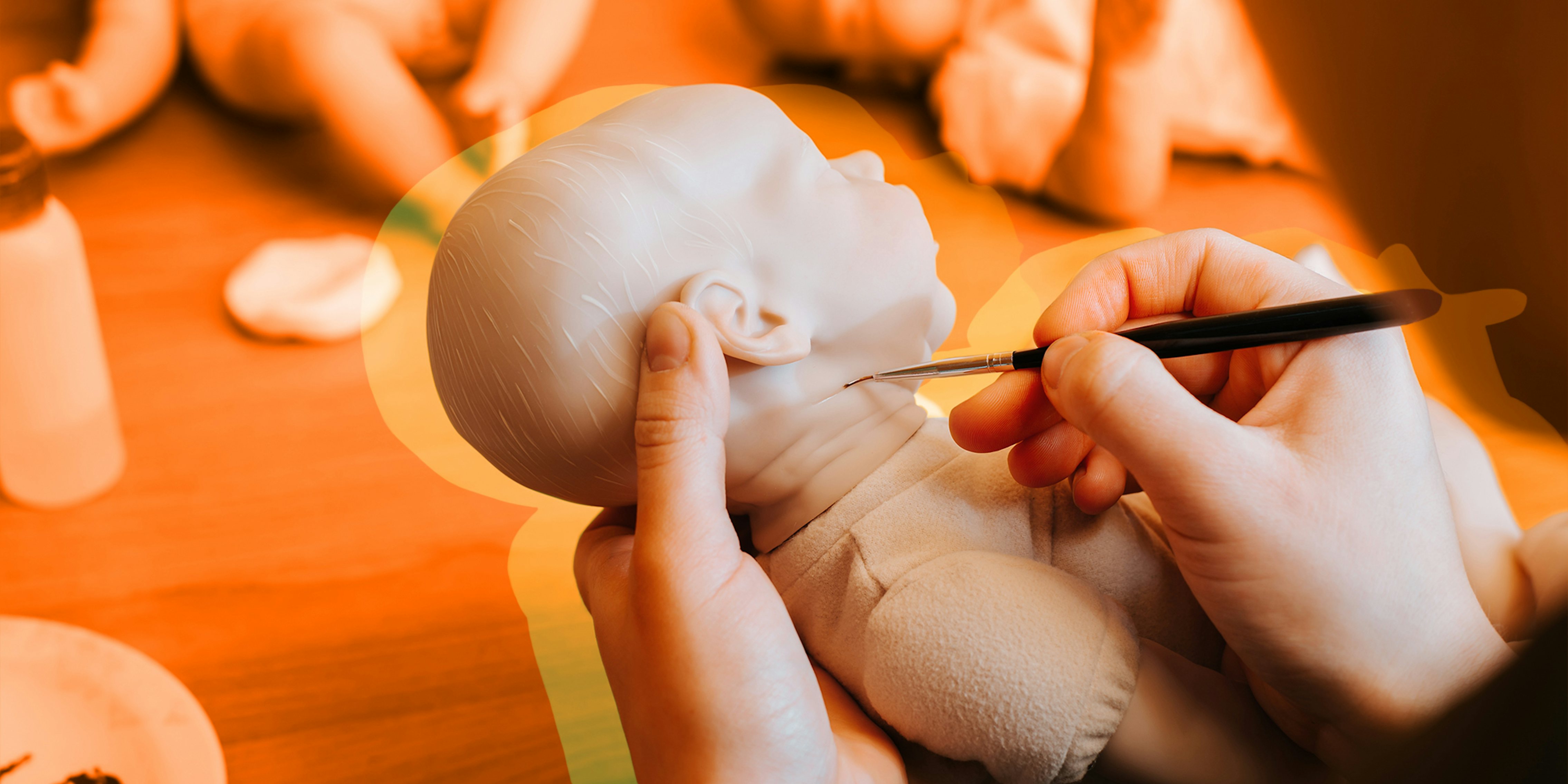 Close-up of female craftsman decorating with brush realistic doll