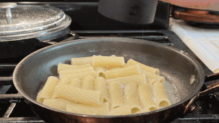 Pepper cannon grinding directly onto cooked pasta.