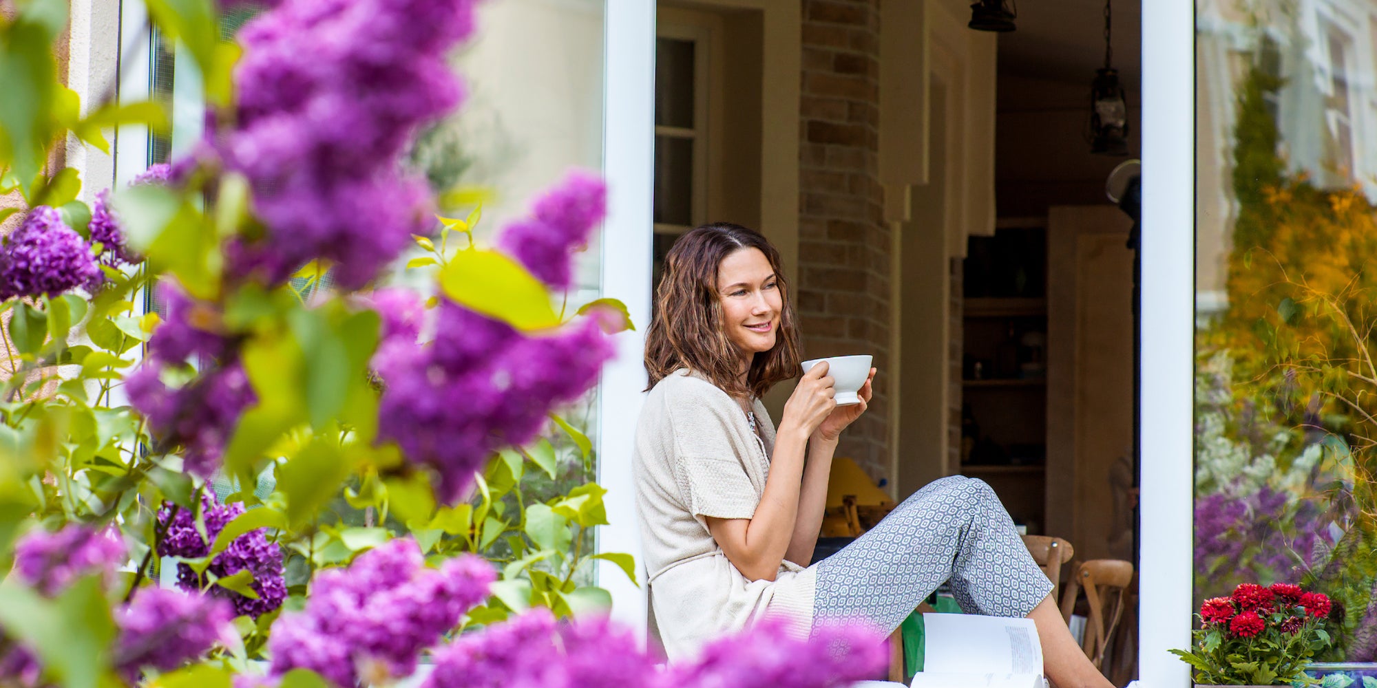 a woman drinking coffee sitting in a window